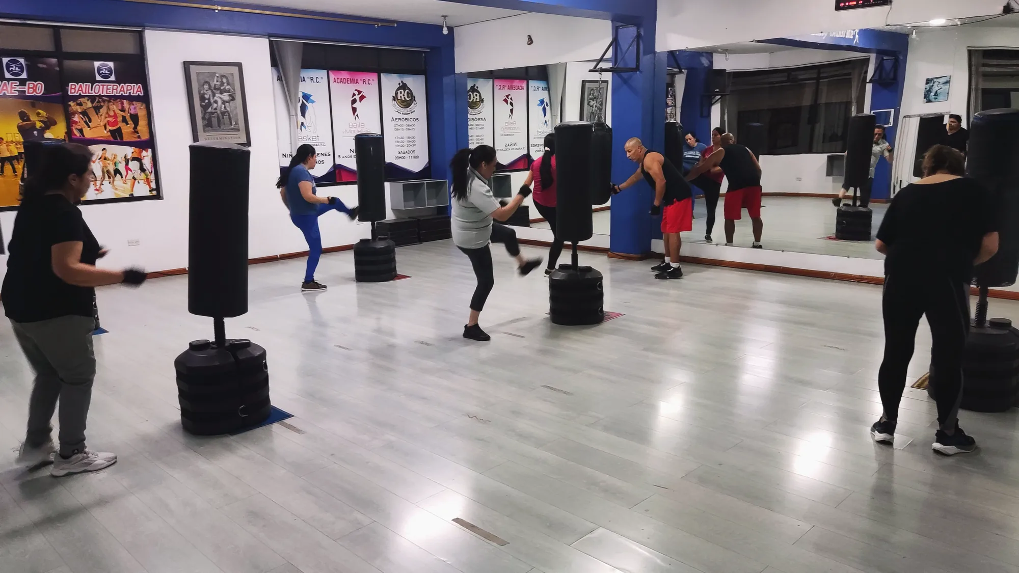 Sala funcional del Gimnasio RC durante una clase de Tae Bo, con sacos de boxeo y espejos.